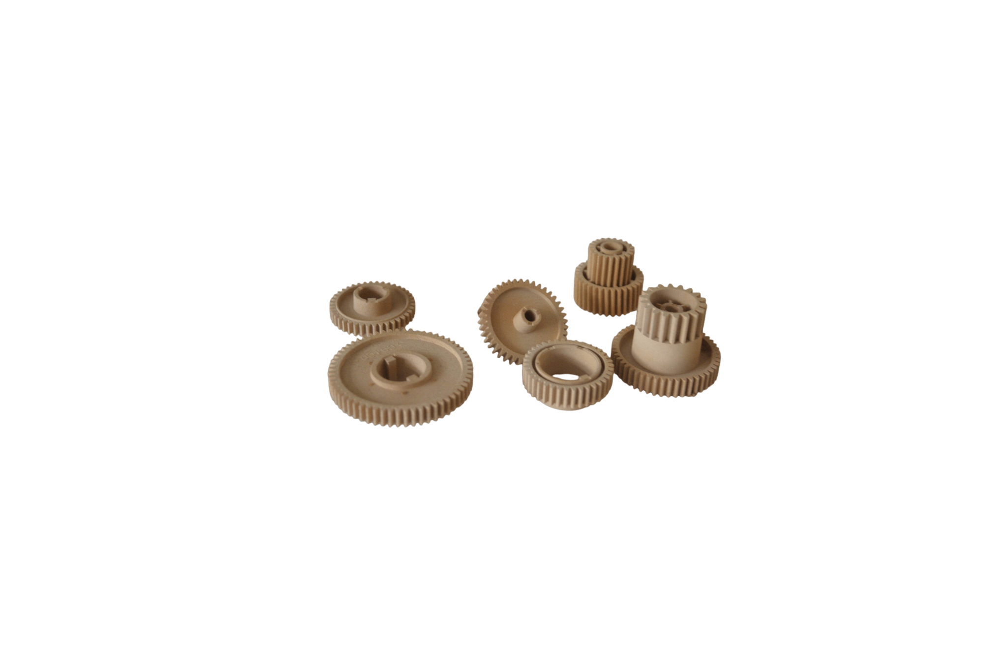 Assorted beige plastic gears of various sizes on a black background, displaying toothed rims and hollow centers.