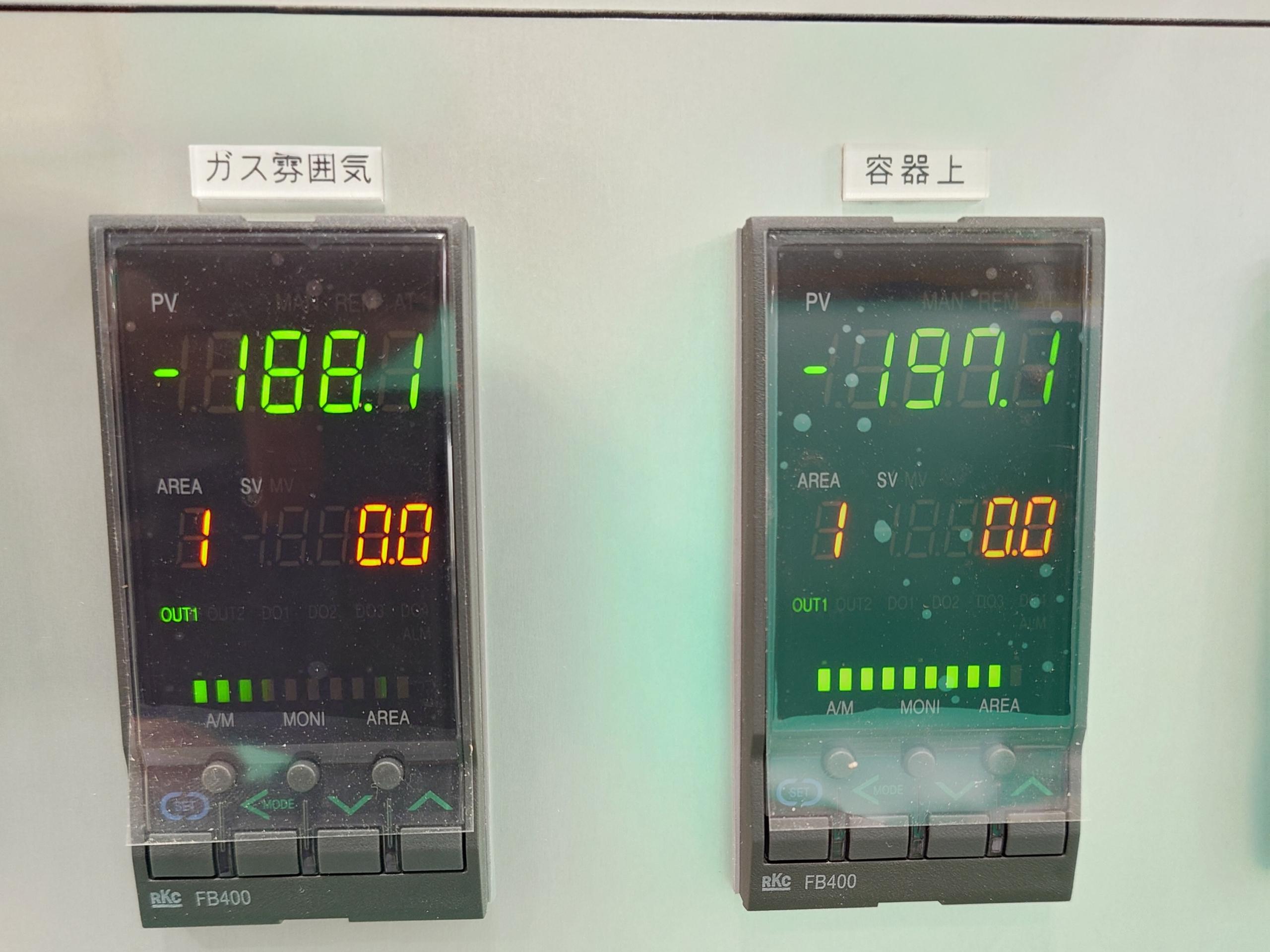 Two digital voltmeters on a control panel display negative voltage readings, with Japanese labels above each meter.
